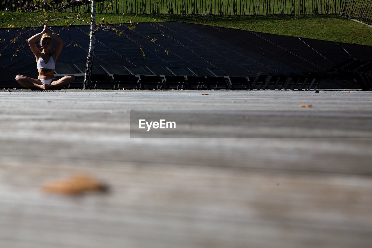 Surface level shot of woman doing yoga while sitting on land