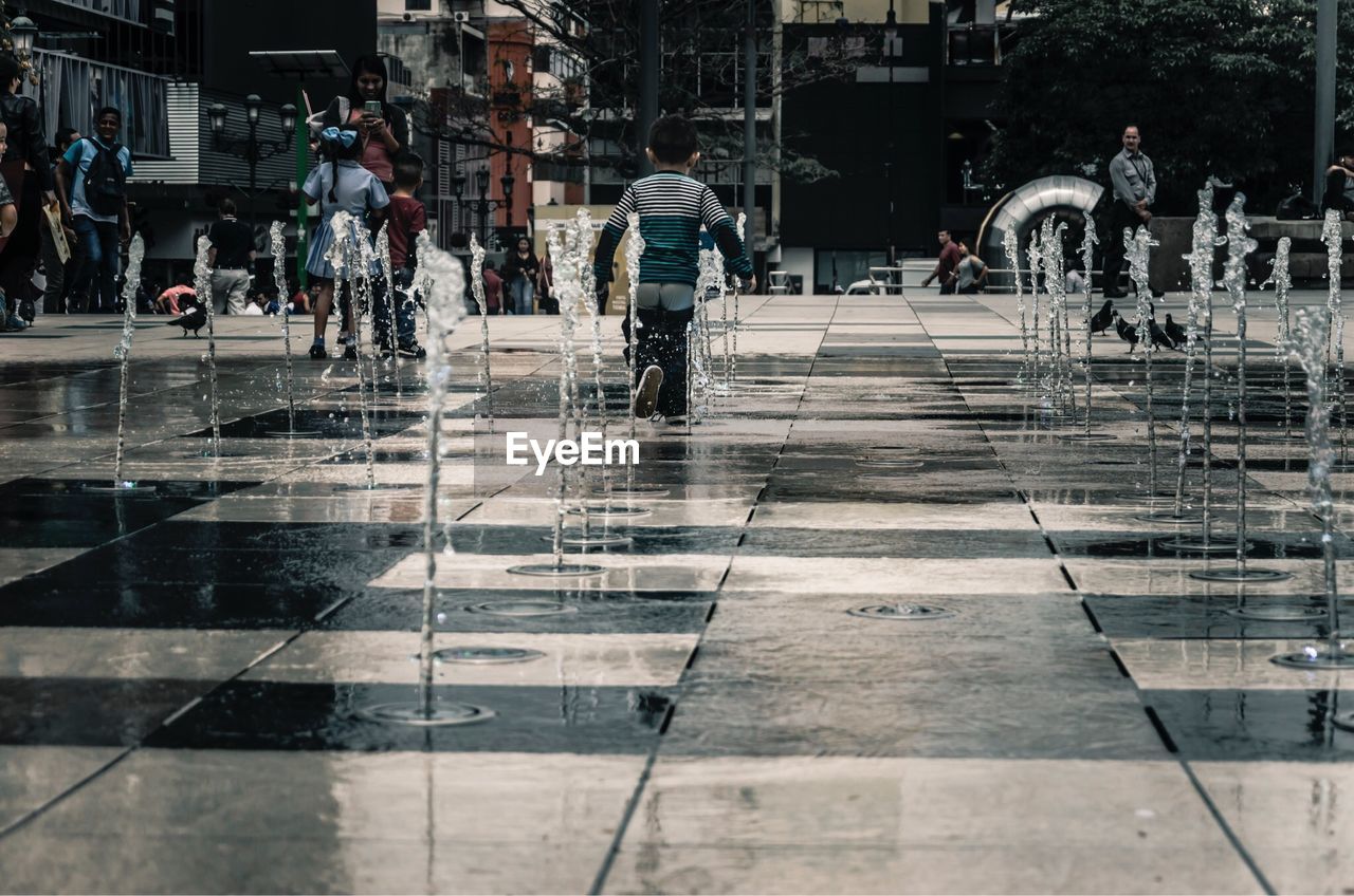 Children at fountains on street in city