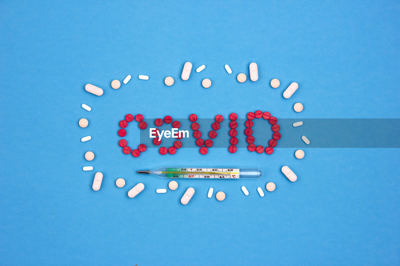 Fighting the coronavirus - thermometer and medicine. capsules and pills on a blue background