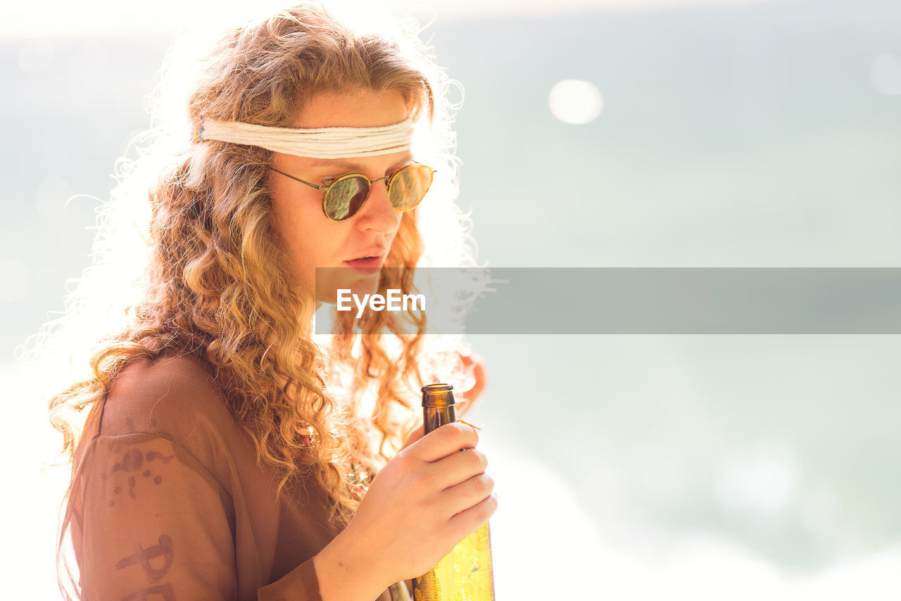 Woman holding beer standing outdoors