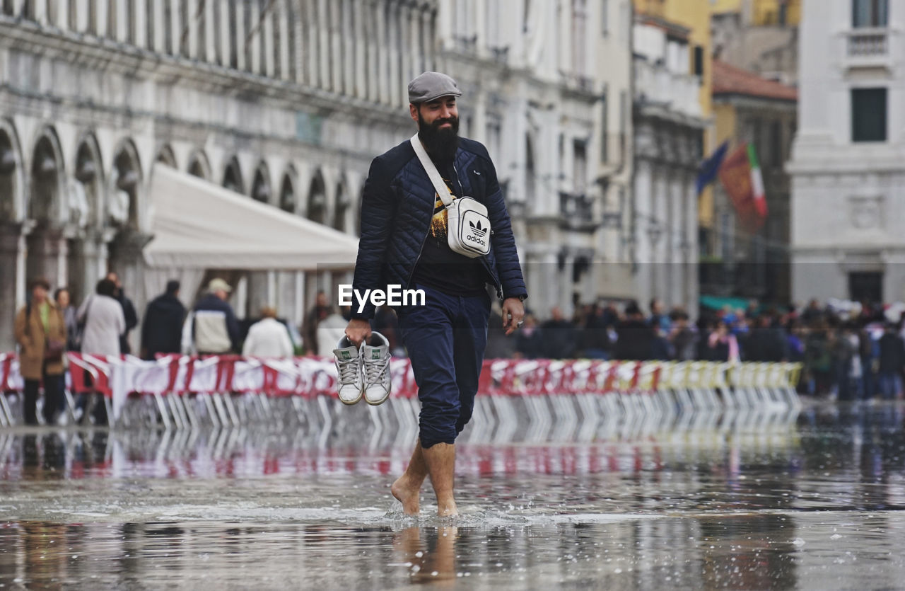 FULL LENGTH OF MAN STANDING ON WET CITY