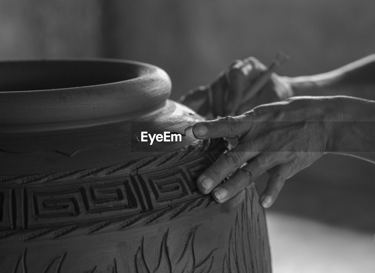 Close-up of potter carving pot at workshop