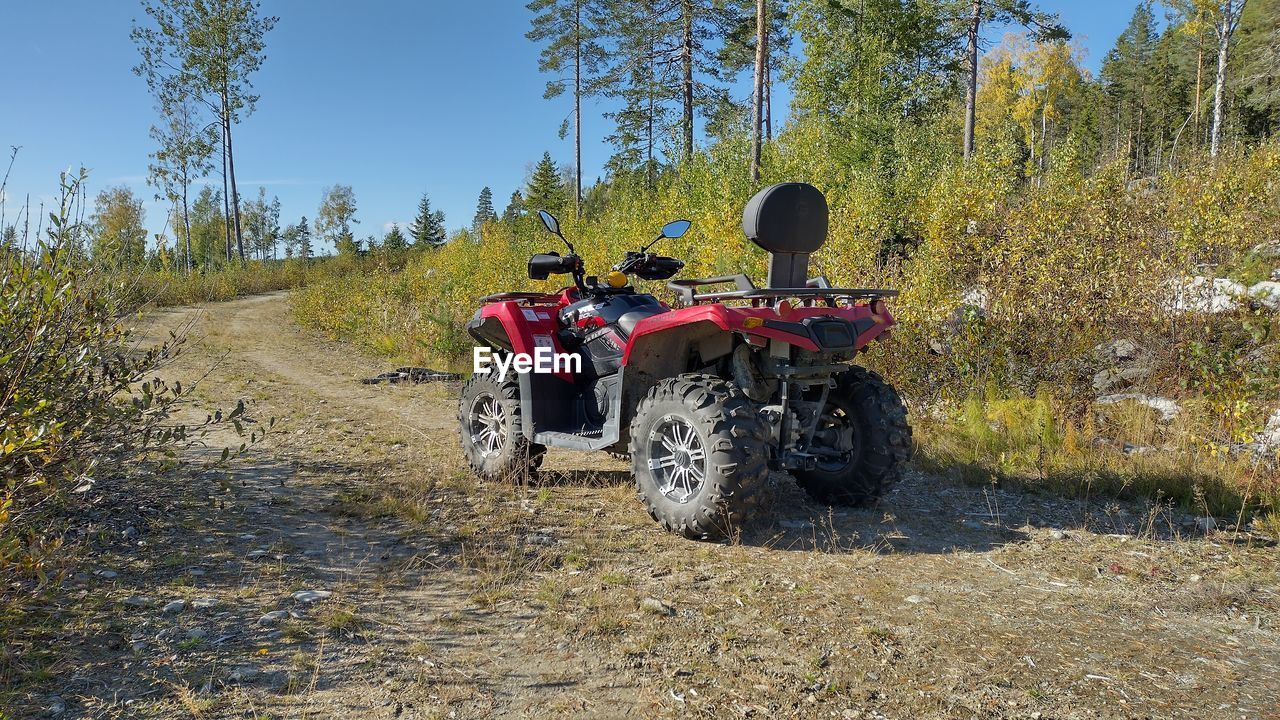 transportation, mode of transportation, all-terrain vehicle, nature, plant, off-roading, tree, land, vehicle, trail, landscape, day, land vehicle, road, motorcycle, dirt, sky, travel, leisure activity, adventure, sports, sunlight, outdoors, dirt road, adult, environment, rural scene, sunny, riding, motorsport, driving, soil, non-urban scene, off-road vehicle, helmet, tire, crash helmet, clear sky