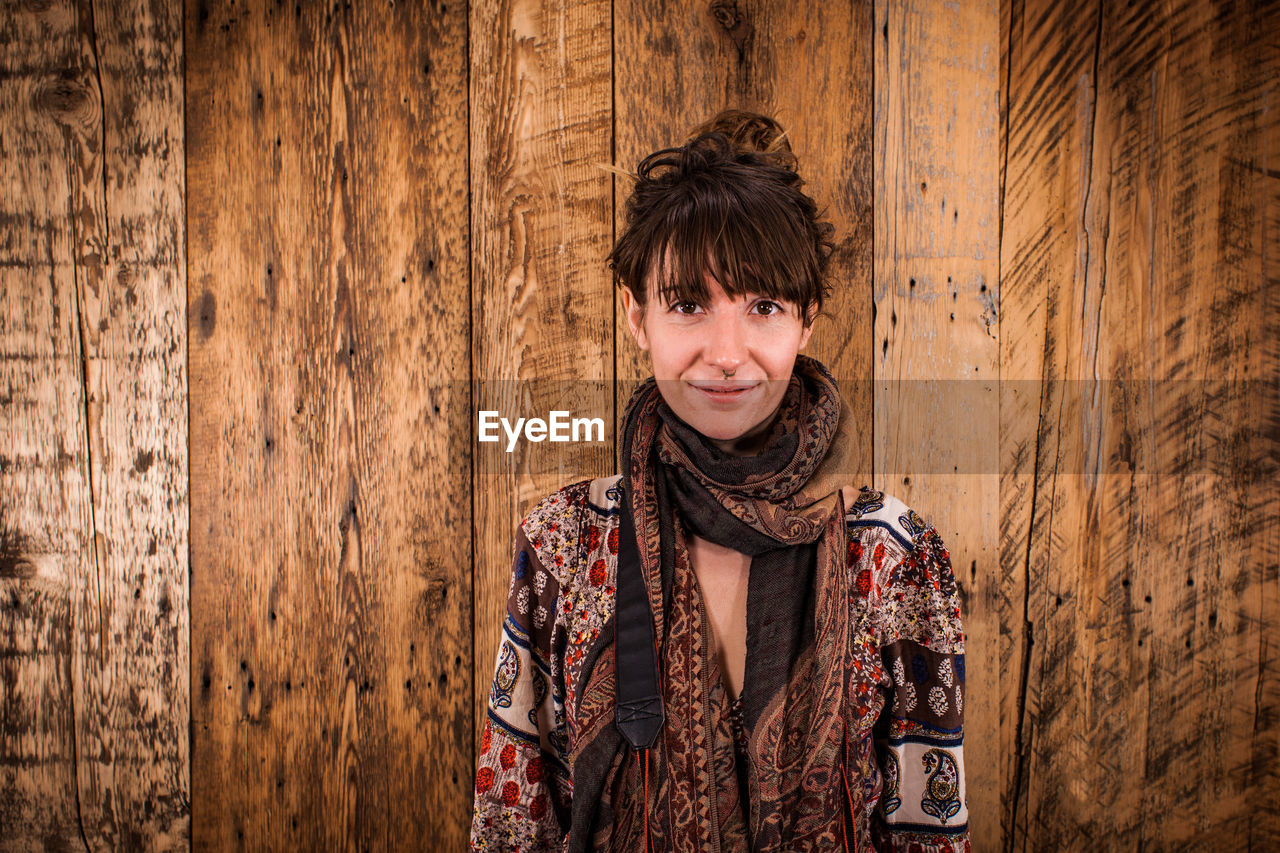 Portrait of woman standing against wooden wall