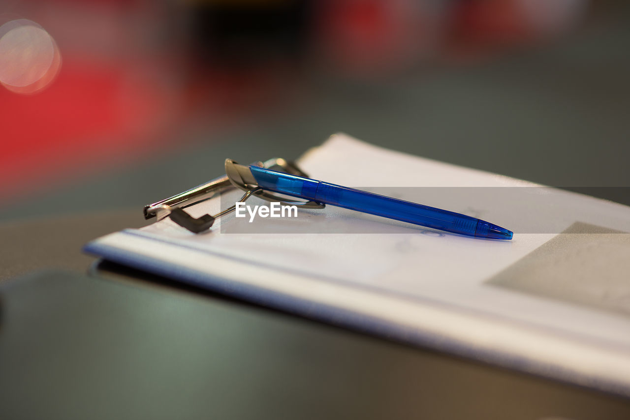 Close-up of pen and file on clipboard at table