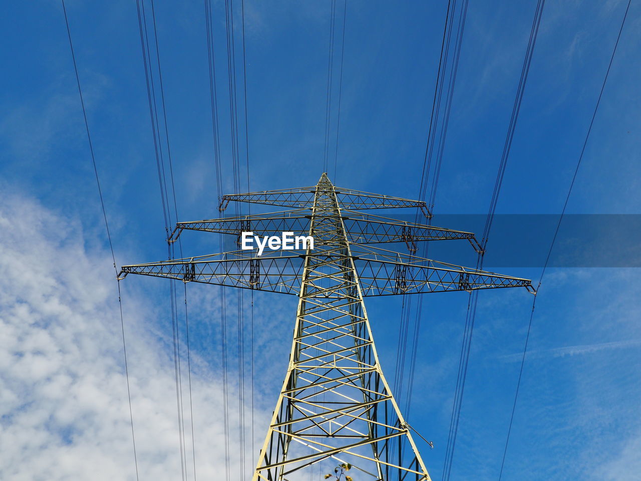 Low angle view of electricity pylon against blue sky