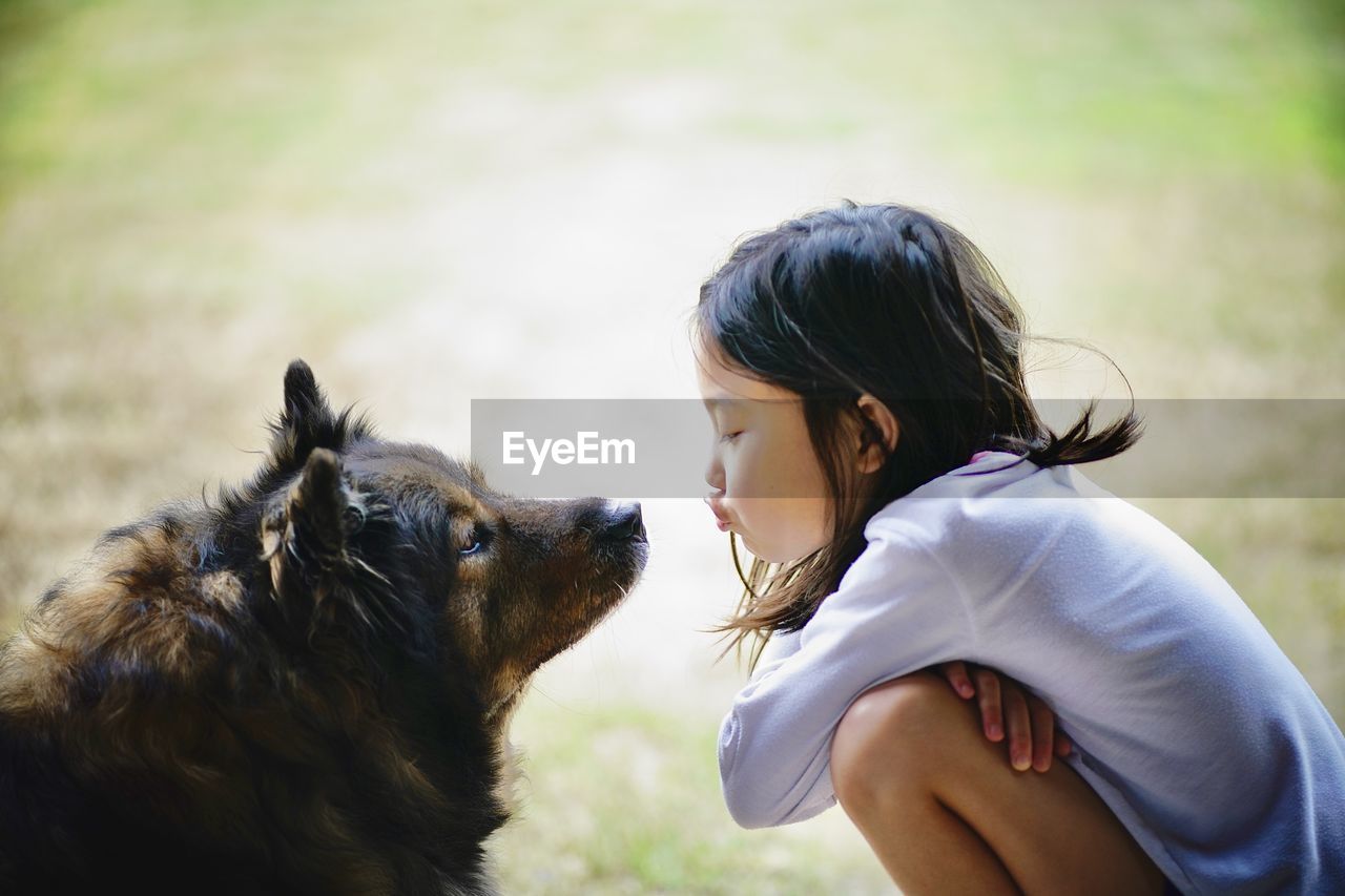 Side view of girl kissing dog