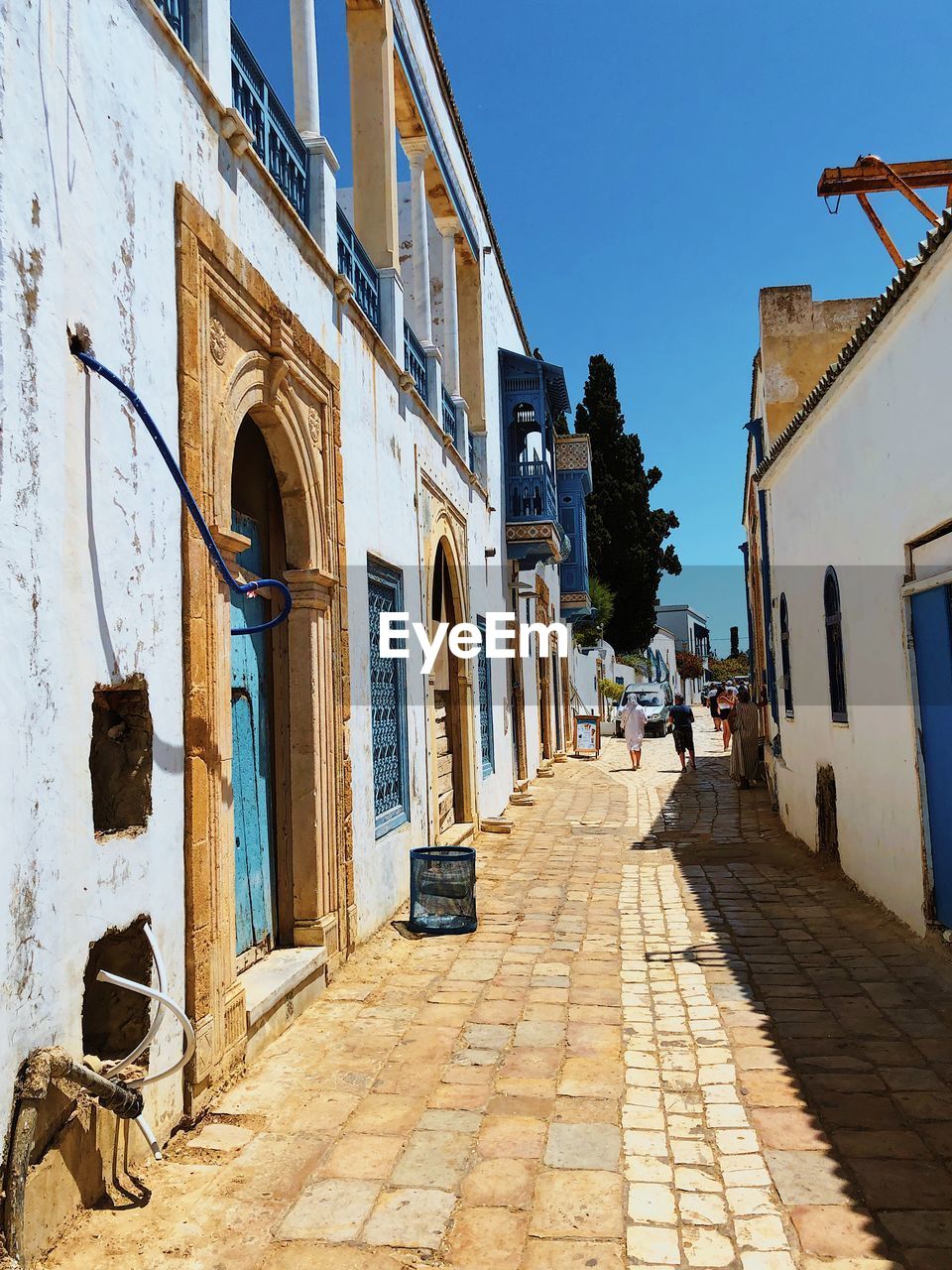 Footpath amidst buildings against blue sky