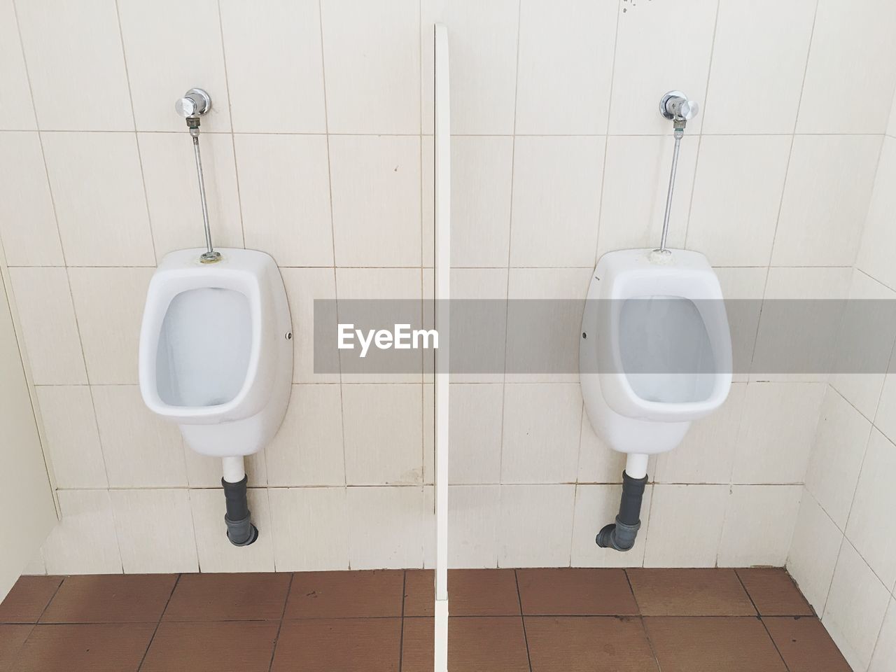 Flushing toilets against tile wall in bathroom