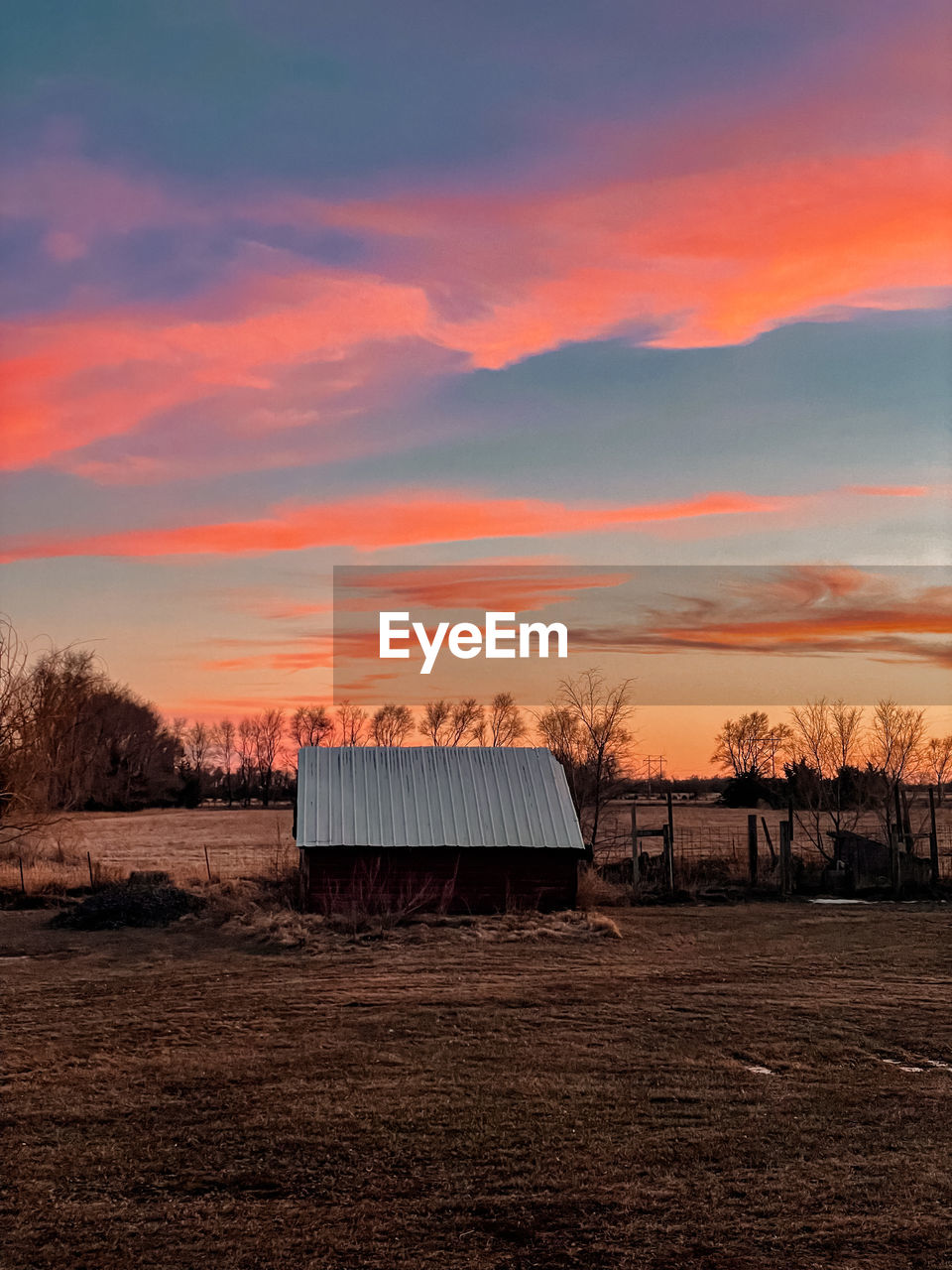 House on field against sky during sunset