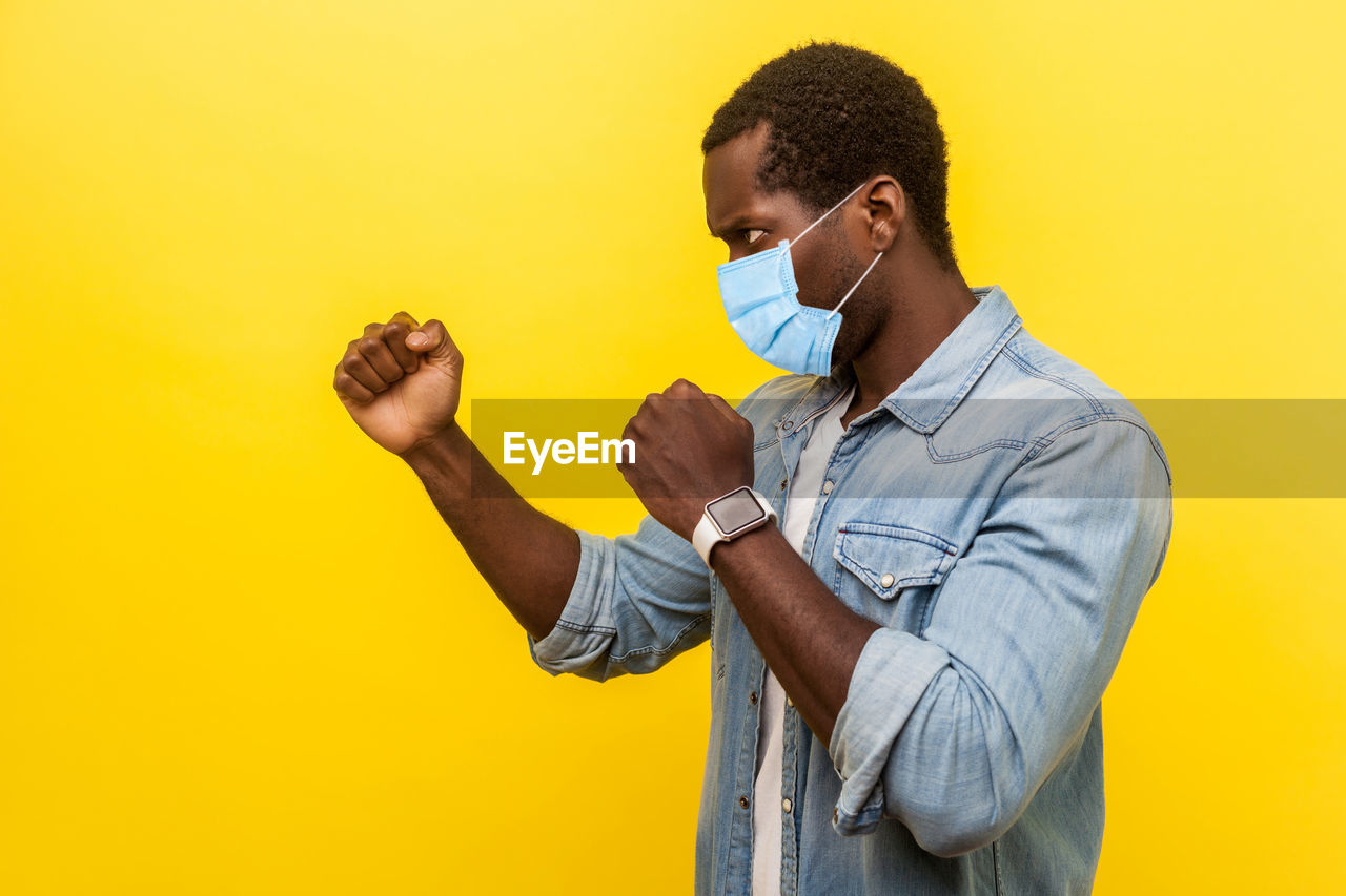 Full length of man standing against yellow background