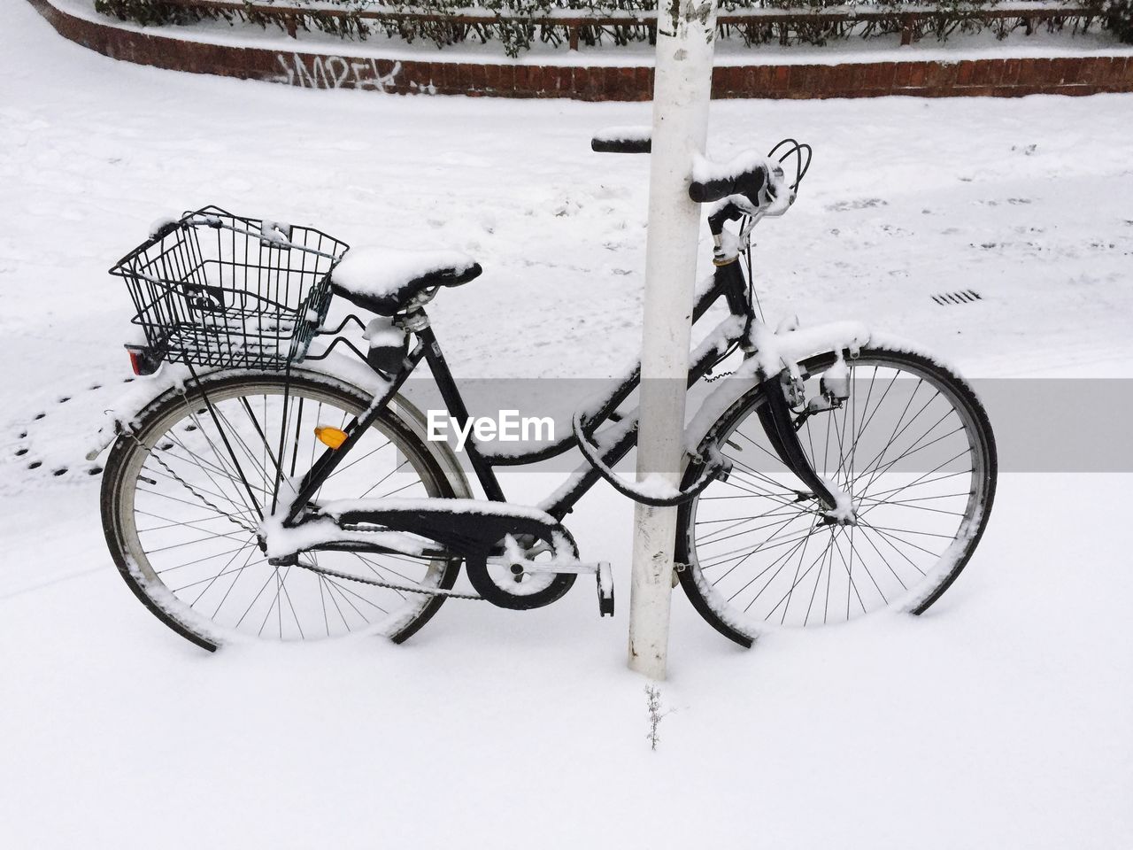 High angle view of bicycle locked by pole during winter