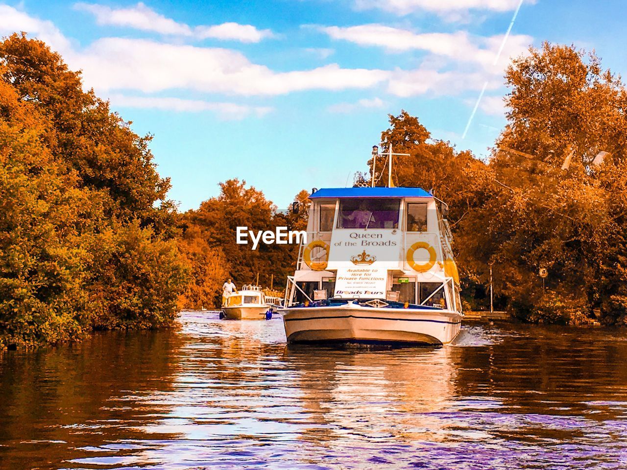 Boat in river by trees against sky