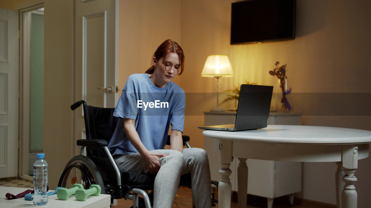 Young woman sitting on wheelchair at home