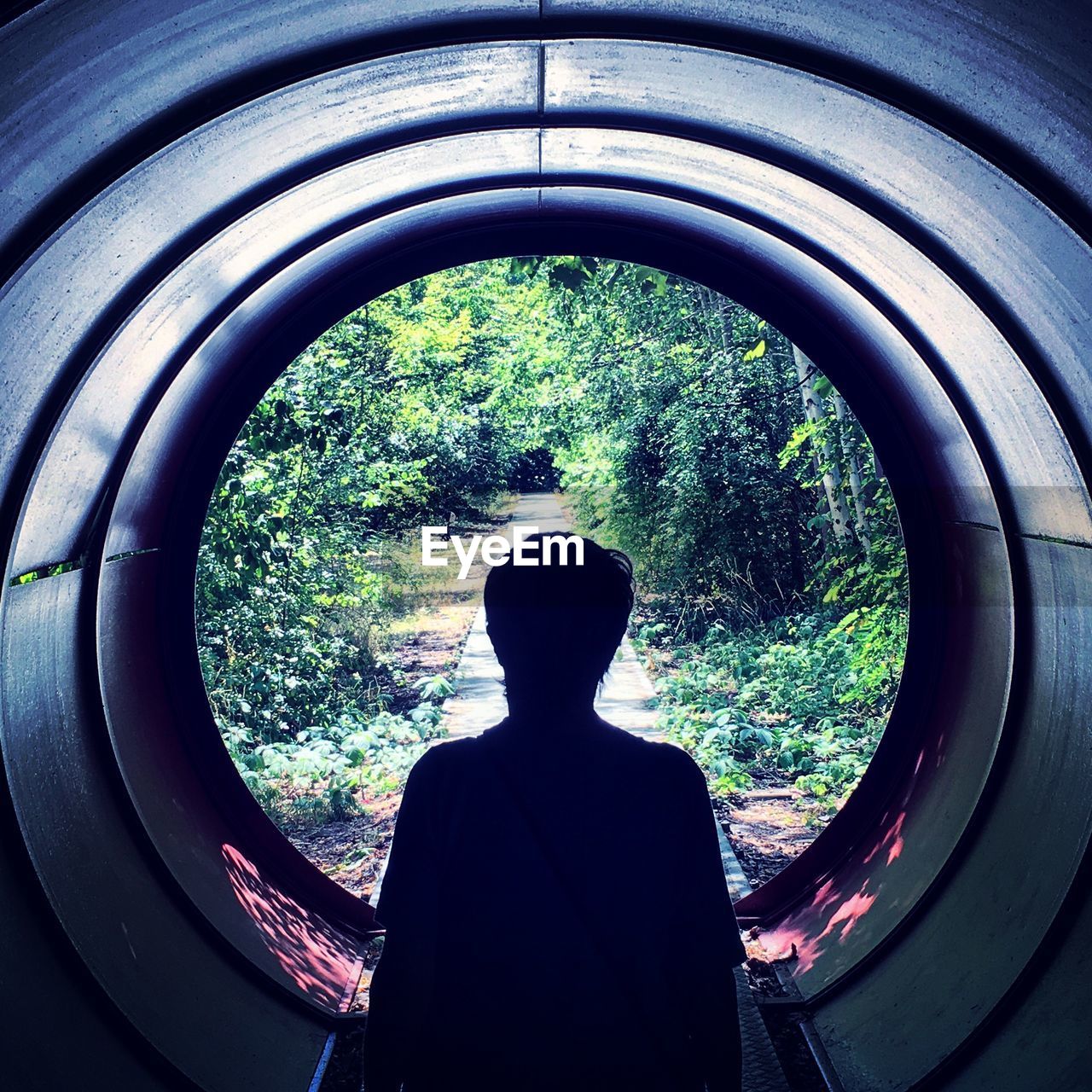 REAR VIEW OF MAN LOOKING THROUGH WINDOW IN TUNNEL
