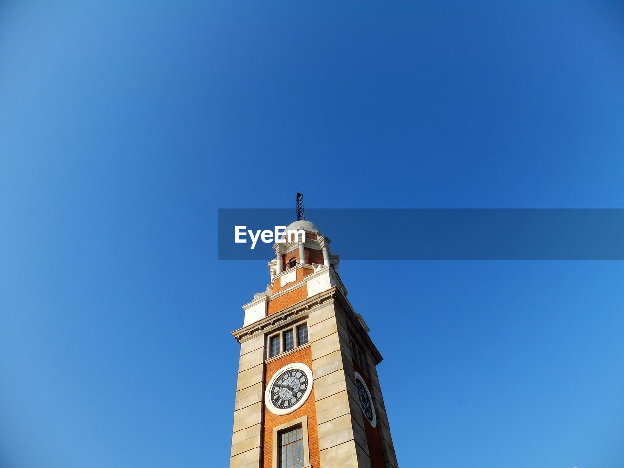 Low angle view of clock tower against clear blue sky on sunny day