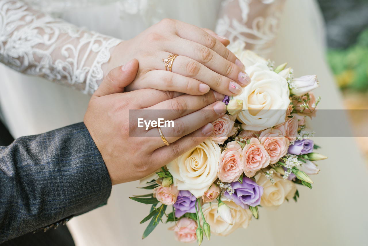 The bride and groom got married and showed their wedding rings over the bride's delicate bouquet