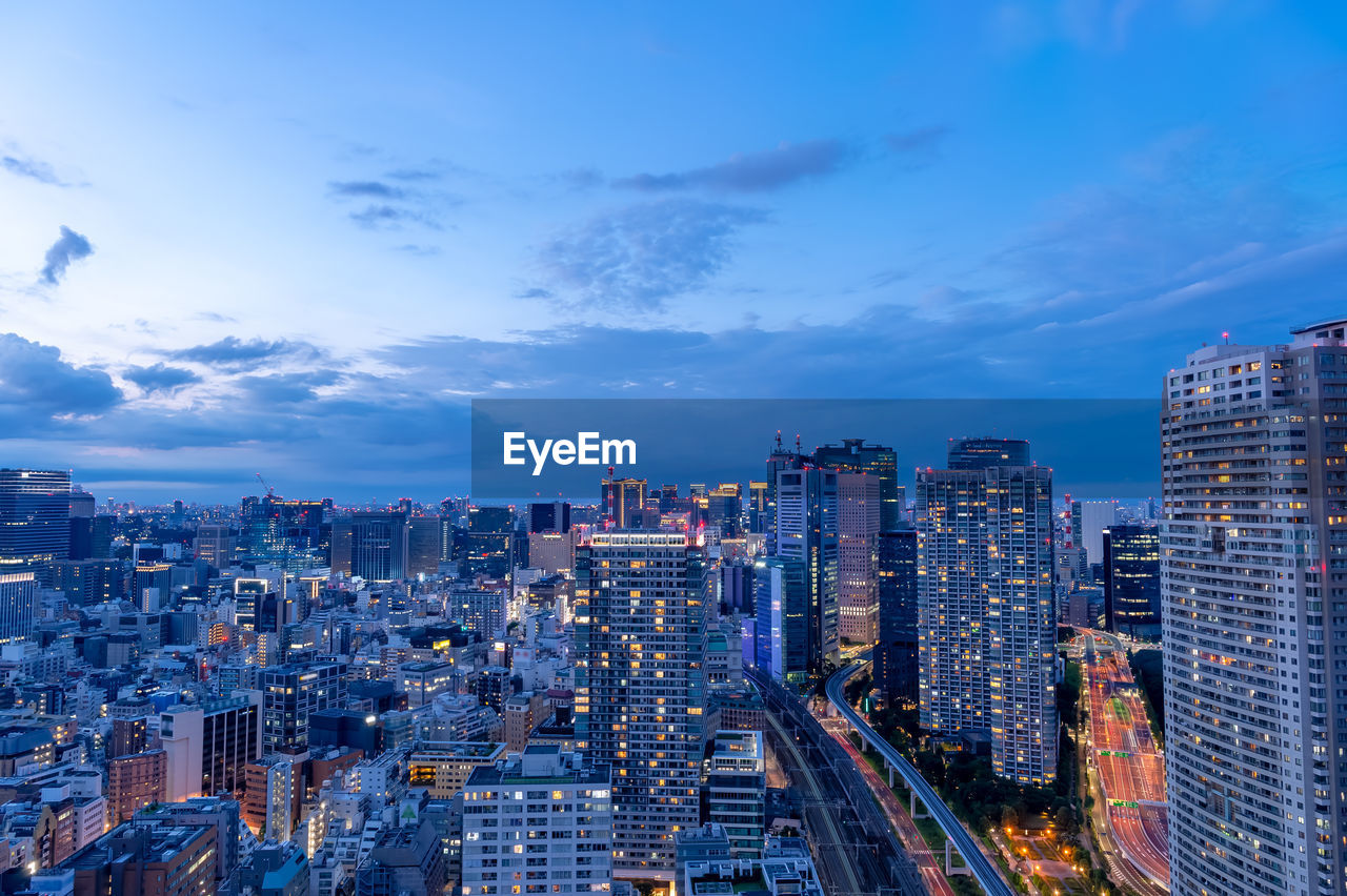 Illuminated buildings in city against sky at dusk