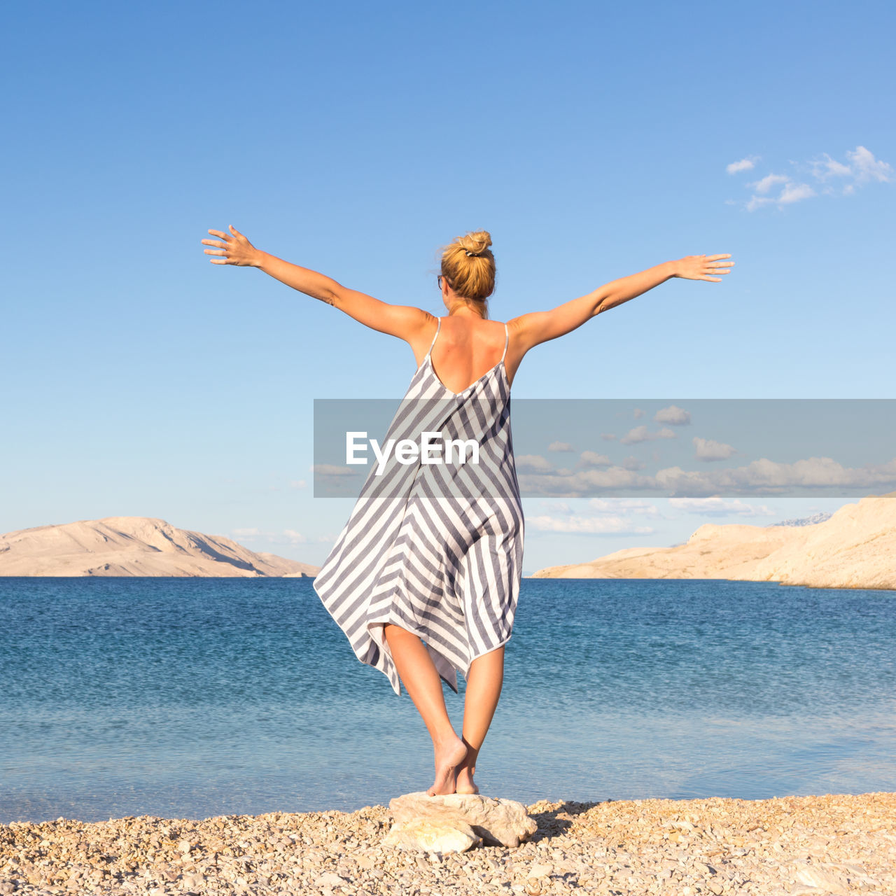 Rear view of woman standing by sea against sky