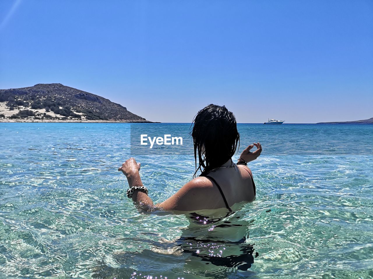 Rear view of woman in sea against clear blue sky