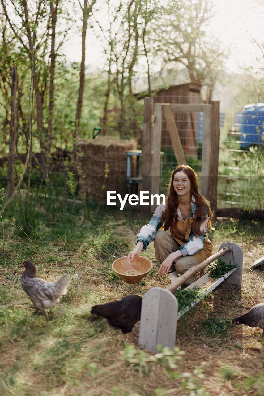 Happy woman feeding chicken in farm