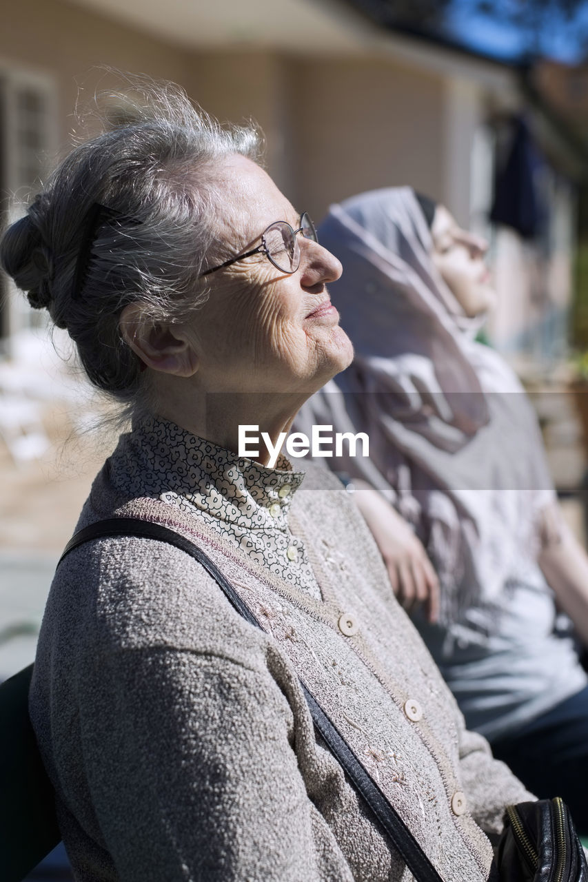 Senior woman and female home caregiver relaxing in front of house