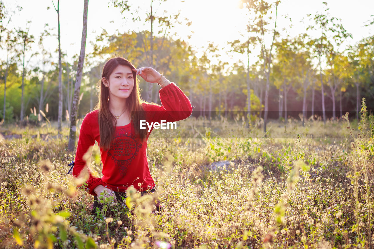 PORTRAIT OF BEAUTIFUL YOUNG WOMAN STANDING IN PARK