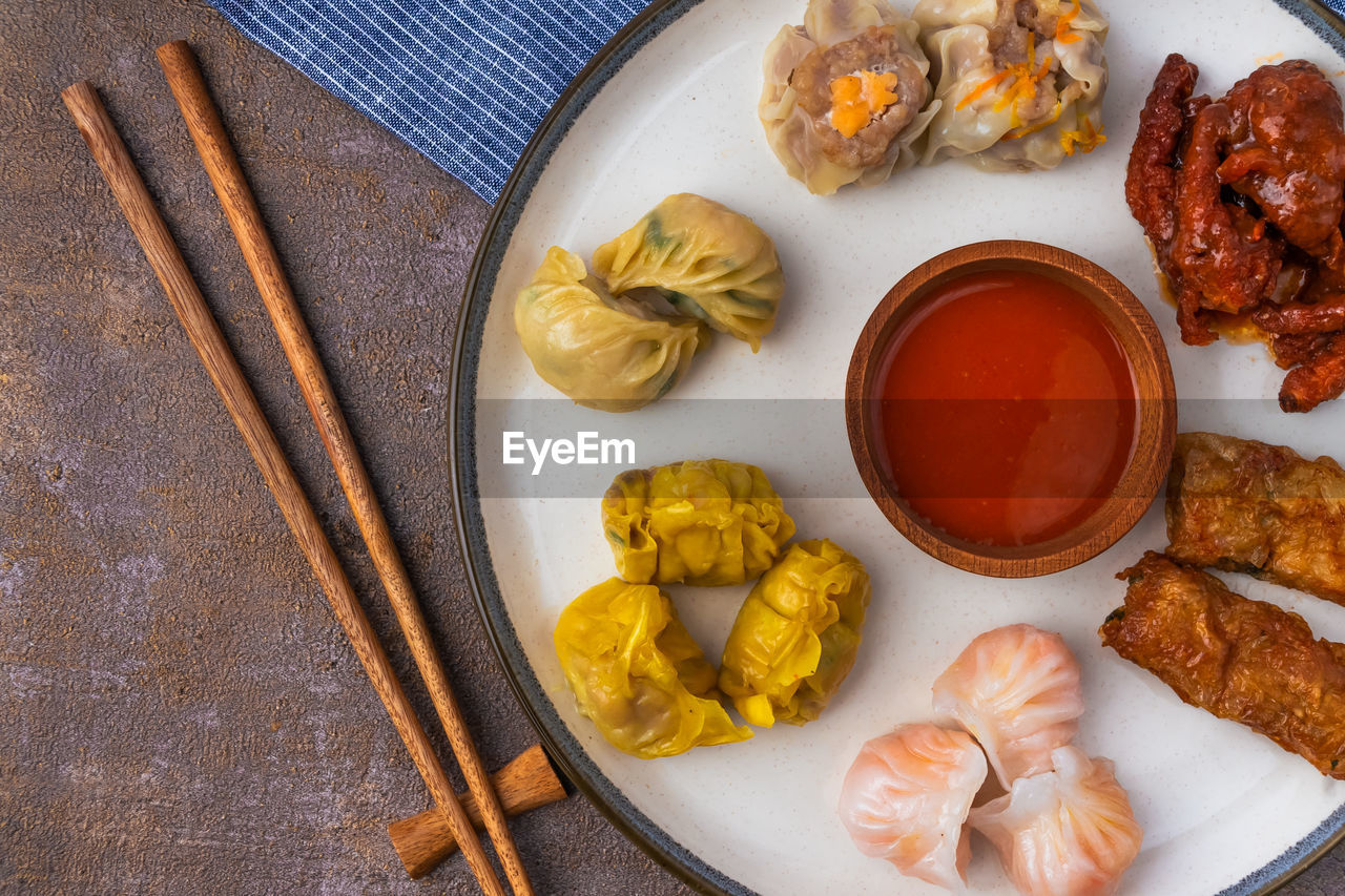 Various variants of dim sum in ceramic plates and wooden chopsticks