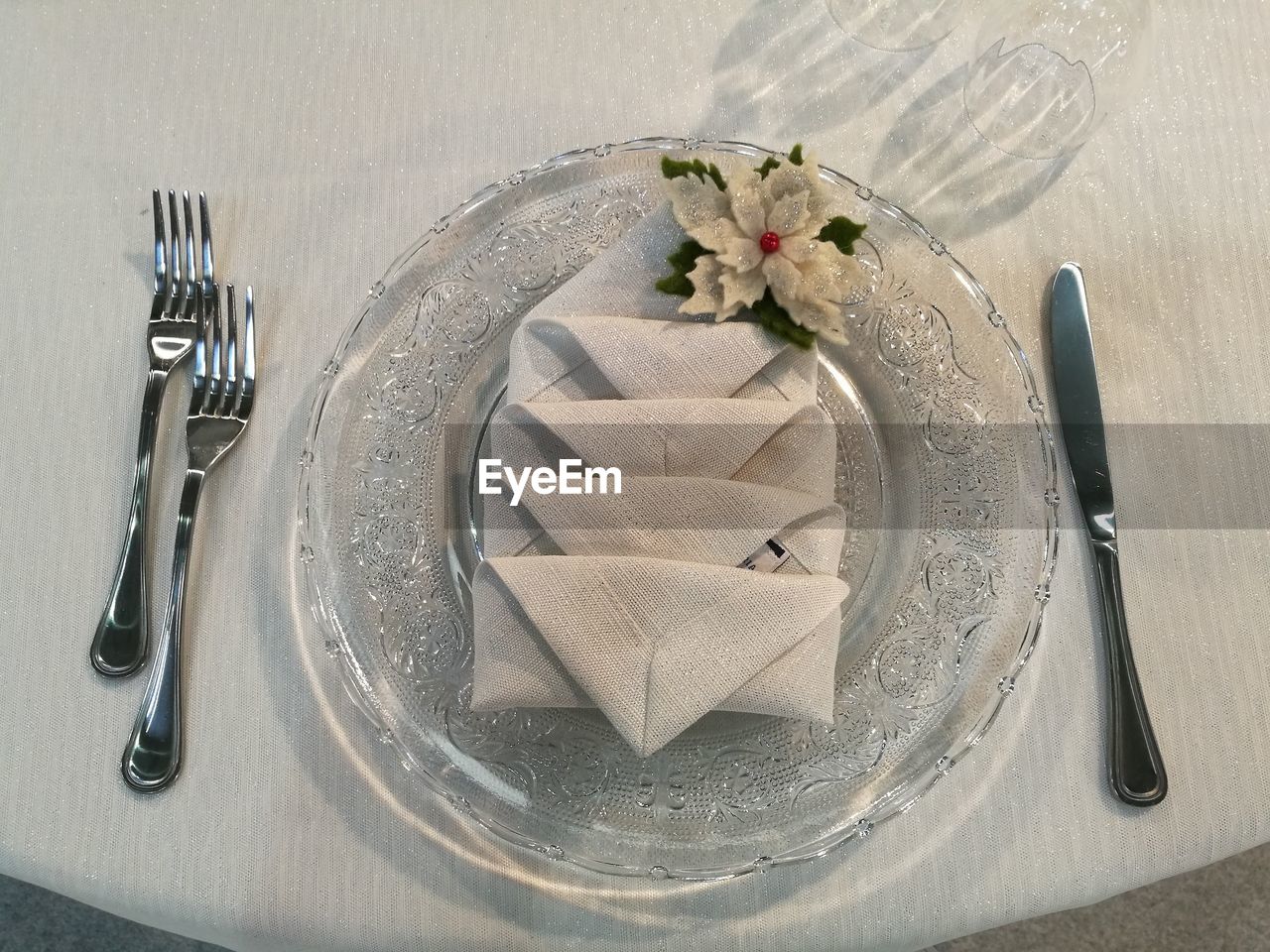 High angle view of folded napkin in glass plate amidst silverware on table at restaurant
