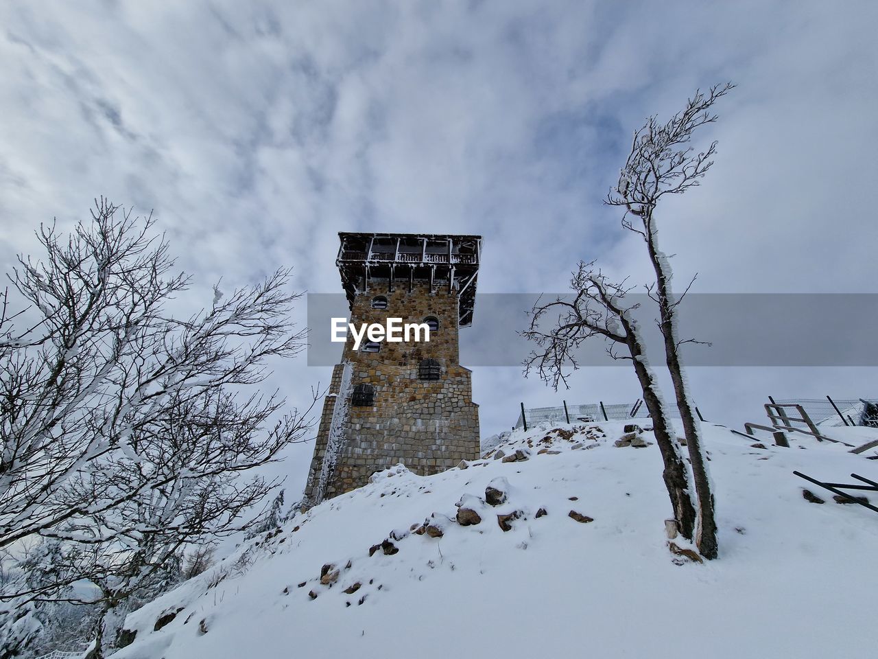 winter, snow, cold temperature, architecture, sky, tree, built structure, nature, cloud, building exterior, history, the past, environment, building, scenics - nature, no people, travel destinations, landscape, plant, land, beauty in nature, tower, mountain, outdoors, travel, tourism, day, forest, low angle view, storm