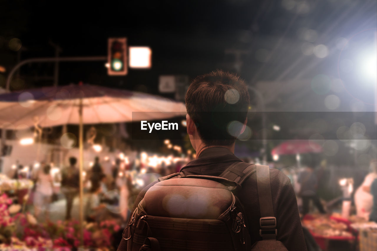 Rear view of man standing on street at night