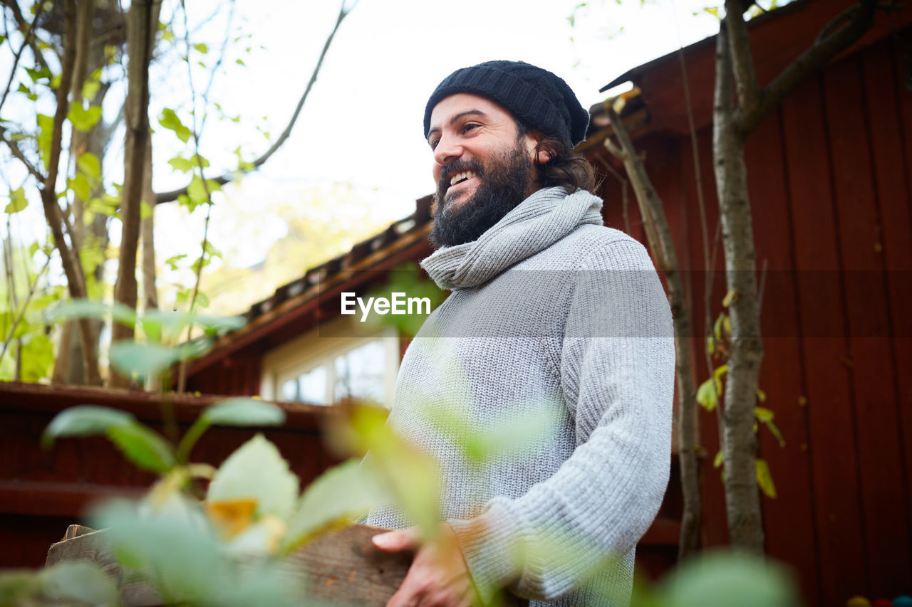 Happy man standing with basket while looking away in yard