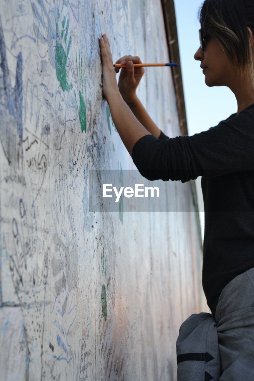 CLOSE-UP OF WOMAN STANDING ON WALL