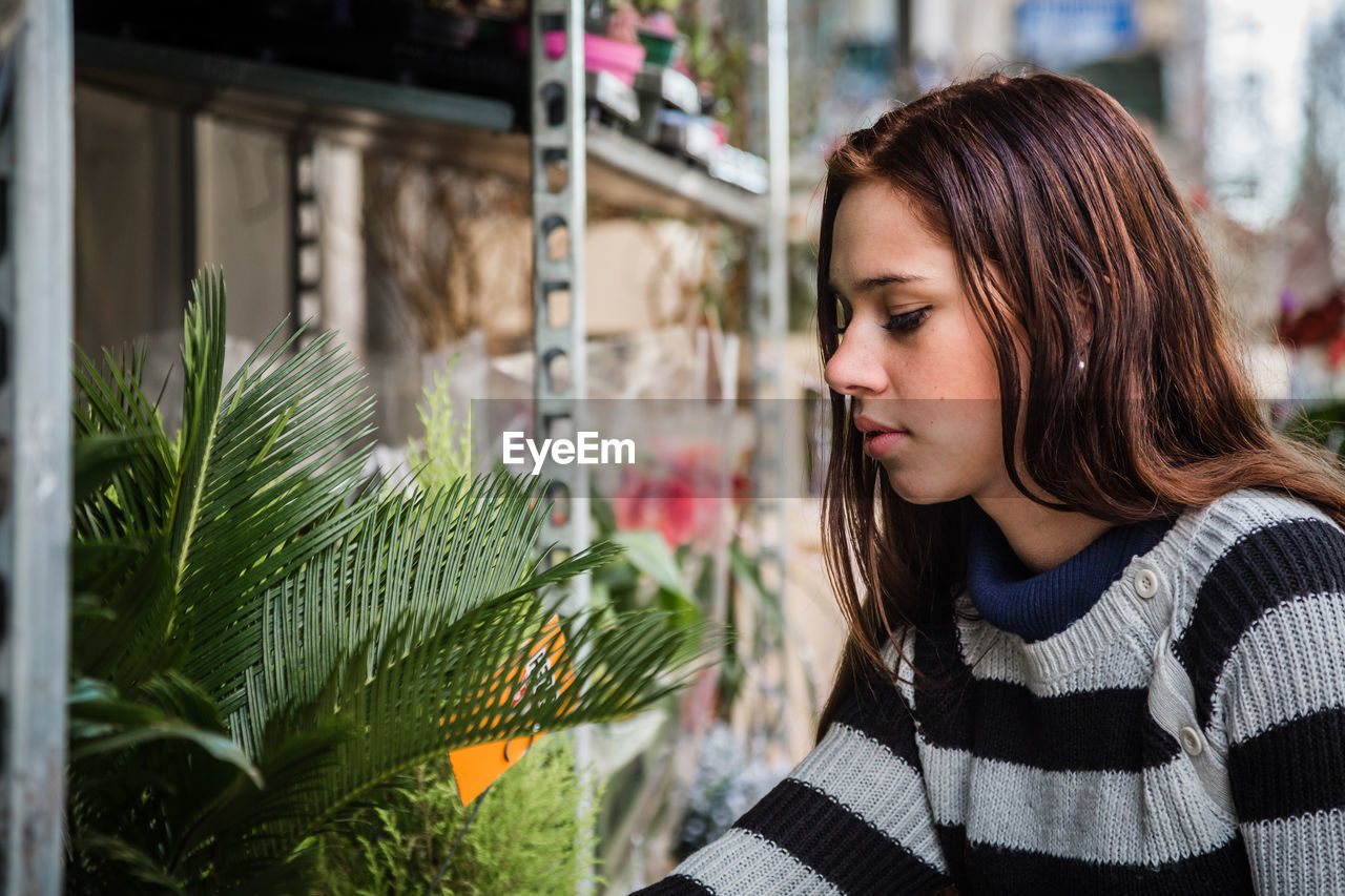 Close-up of young woman with plants at flower shop