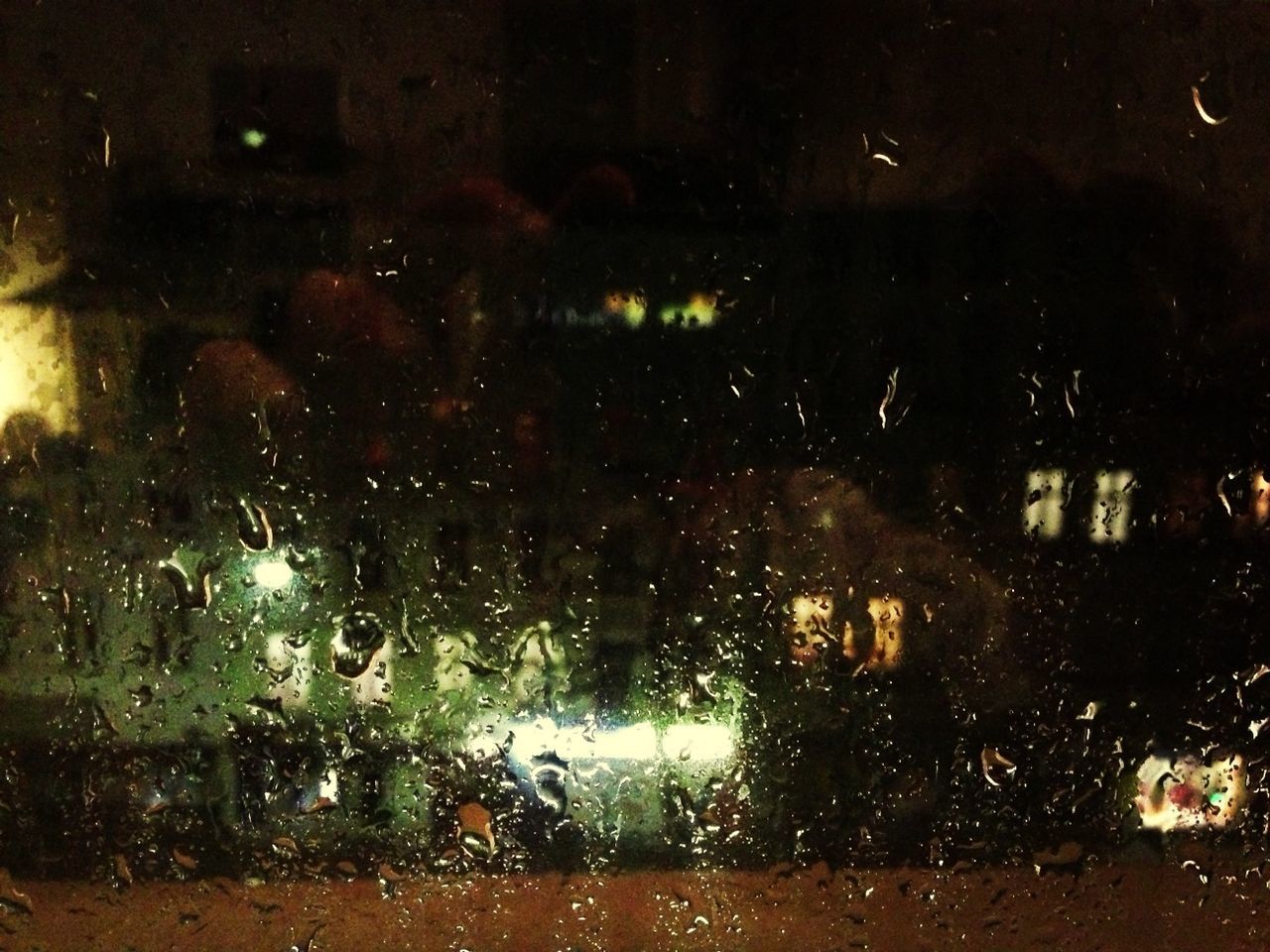 Illuminated city seen through wet glass