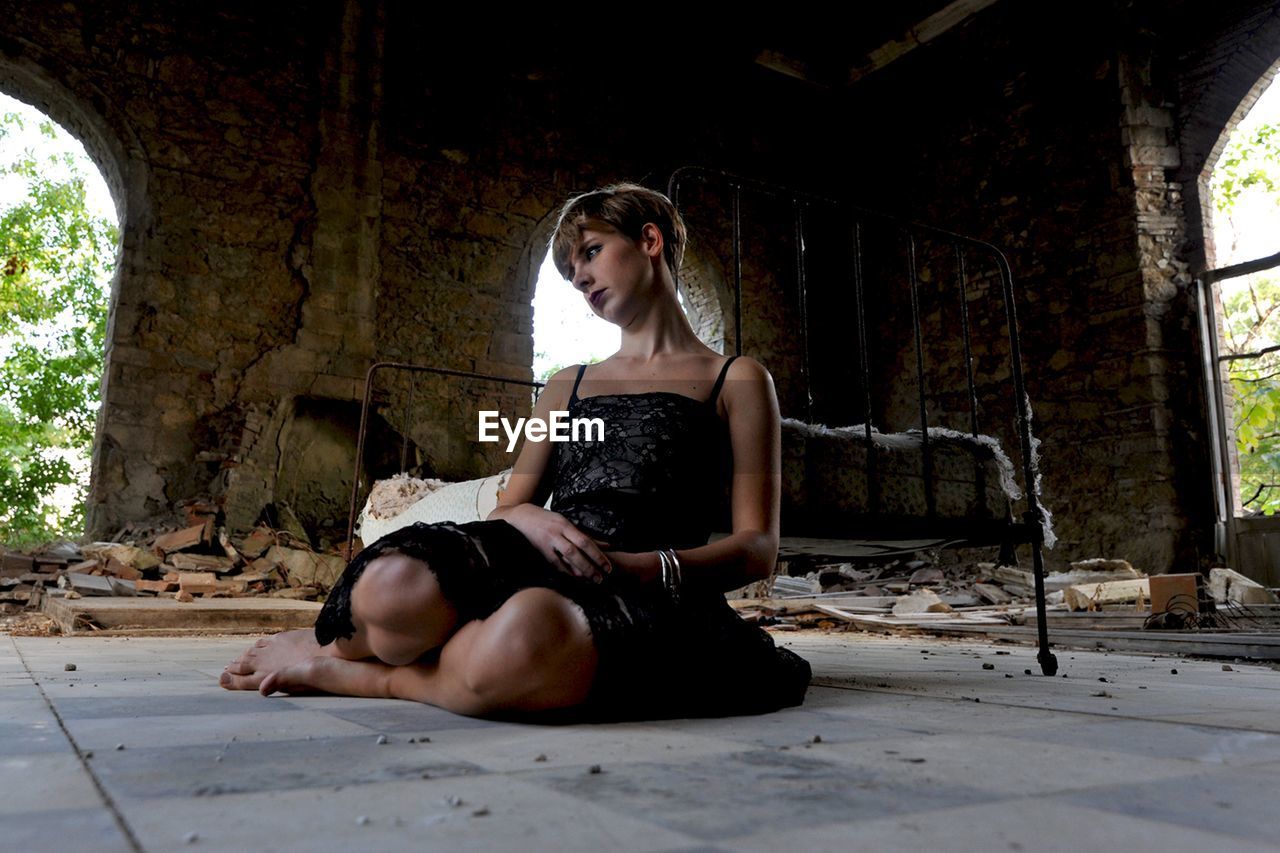 Thoughtful woman sitting on abandoned house floor