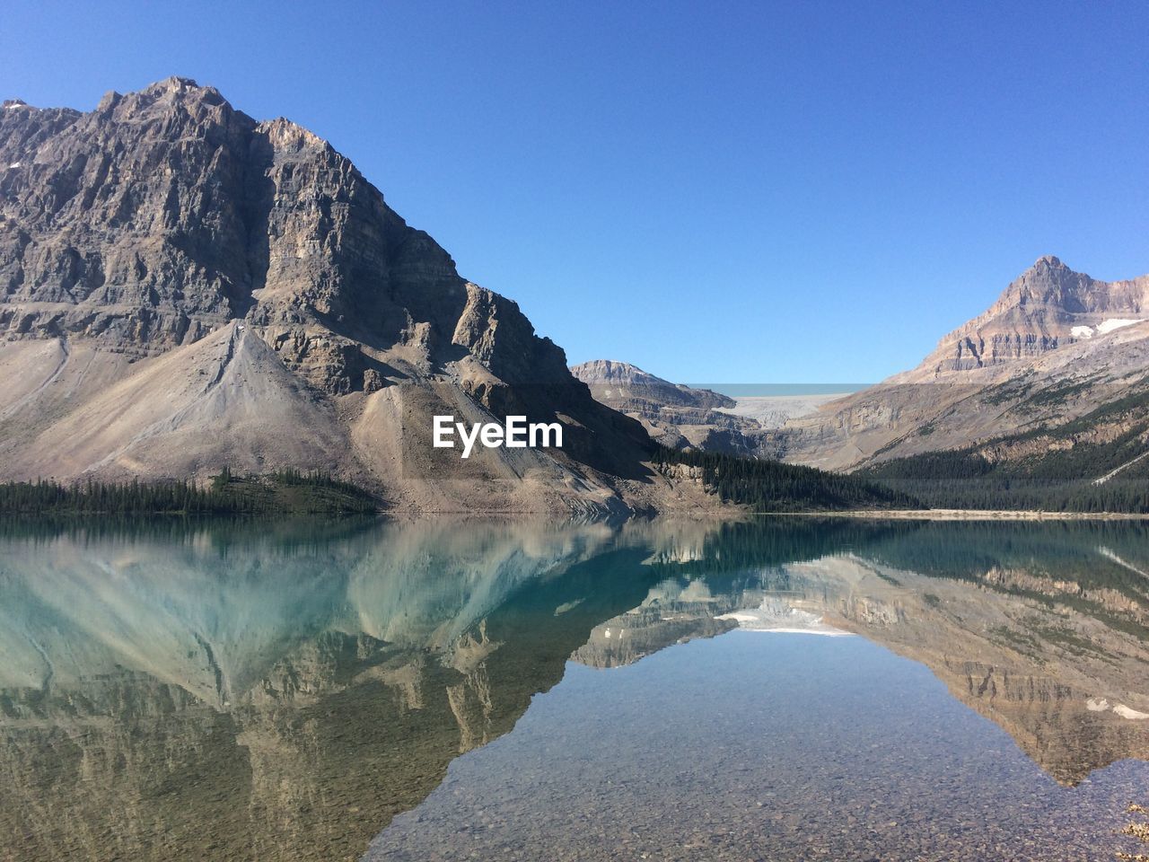 Scenic view of lake and mountains against clear blue sky