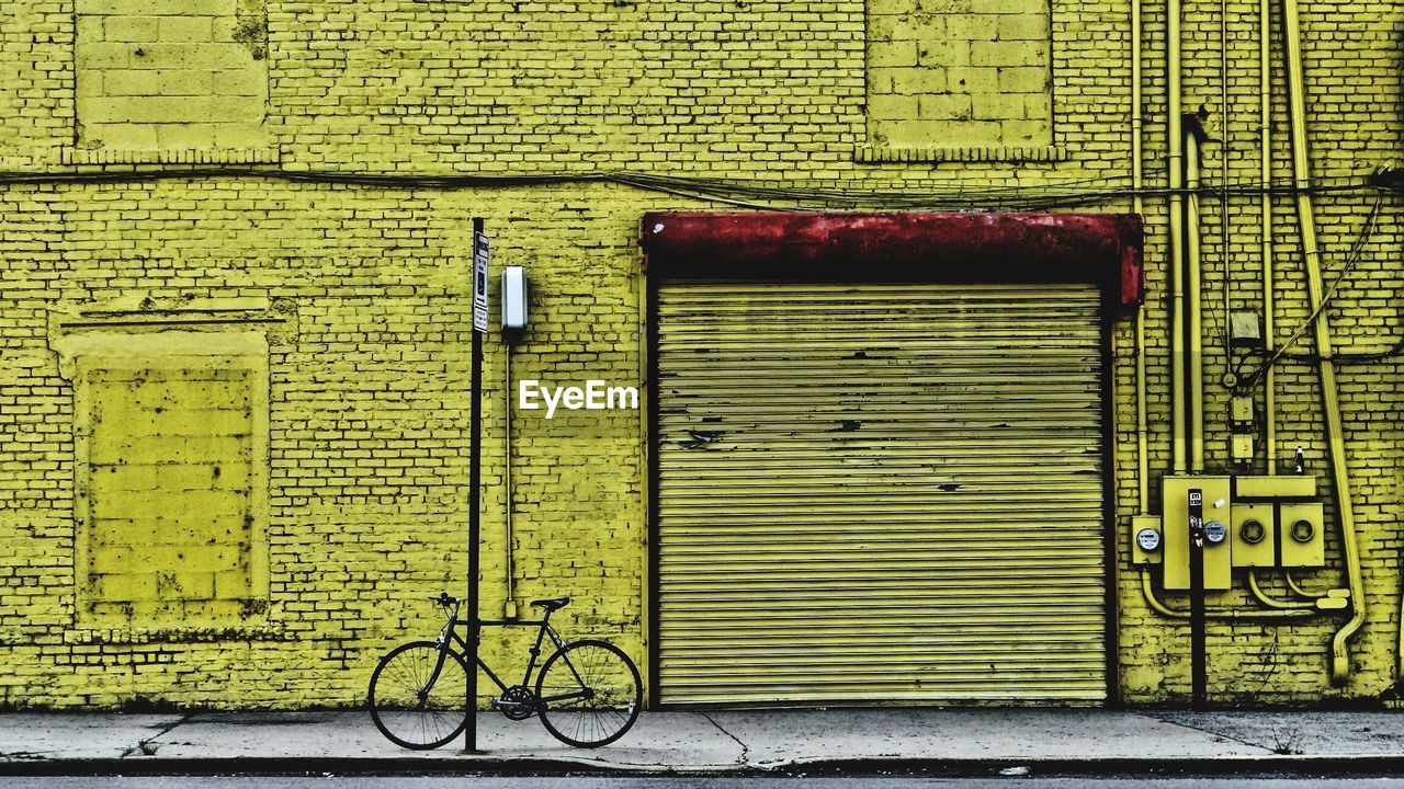 Bicycle parked by yellow painted building