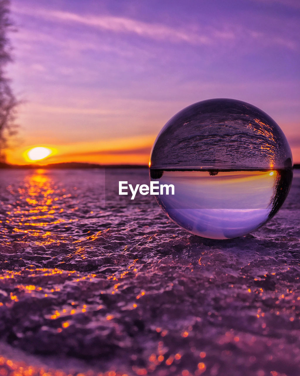 Close-up of crystal ball on water against sky during sunset