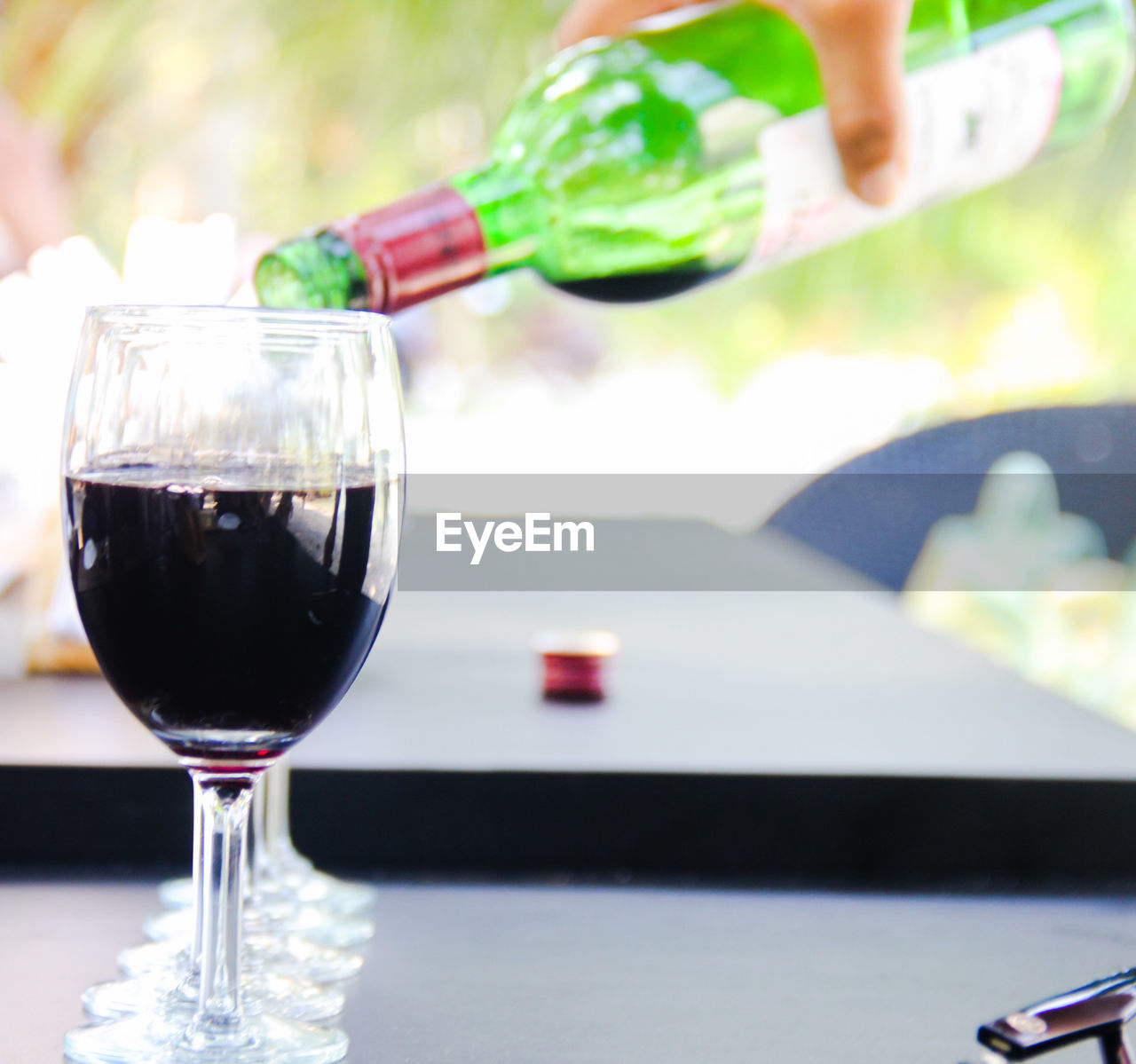 Cropped hand pouring wine in glass on table