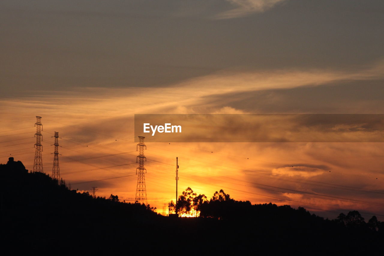 SILHOUETTE ELECTRICITY PYLON AGAINST ORANGE SKY