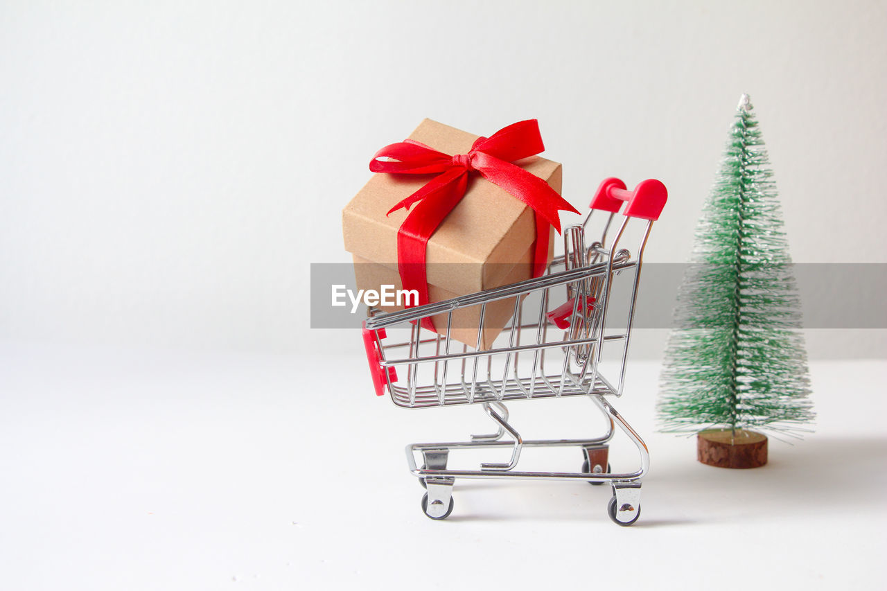 close-up of christmas decoration in shopping cart against white background