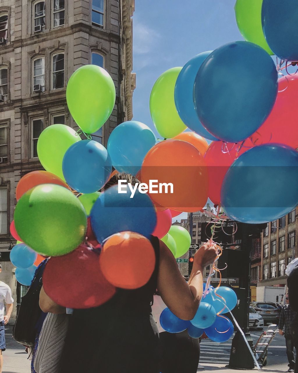 MULTI COLORED BALLOONS IN CITY AGAINST BUILDINGS