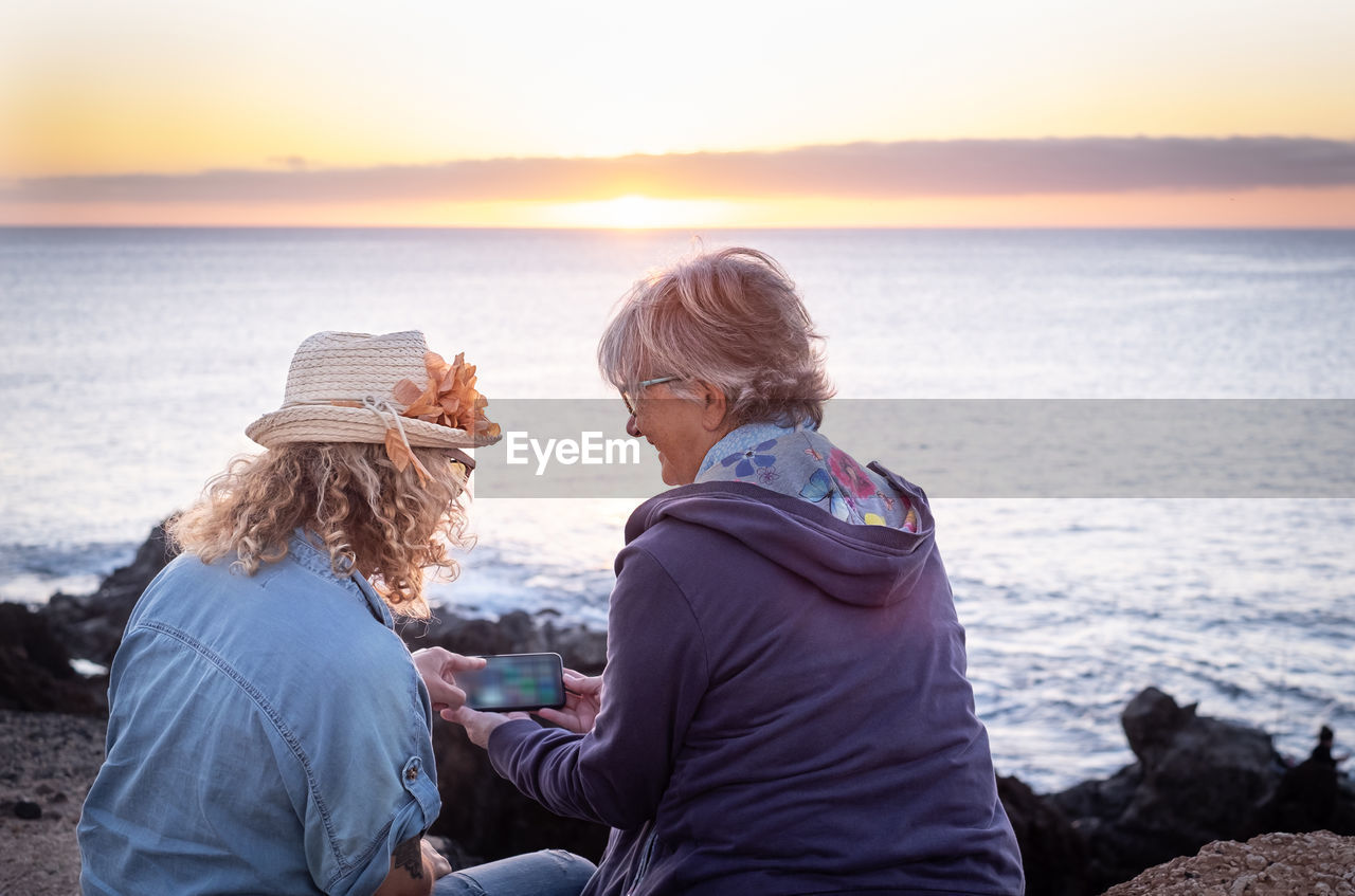 Rear view of people looking at sea against sky