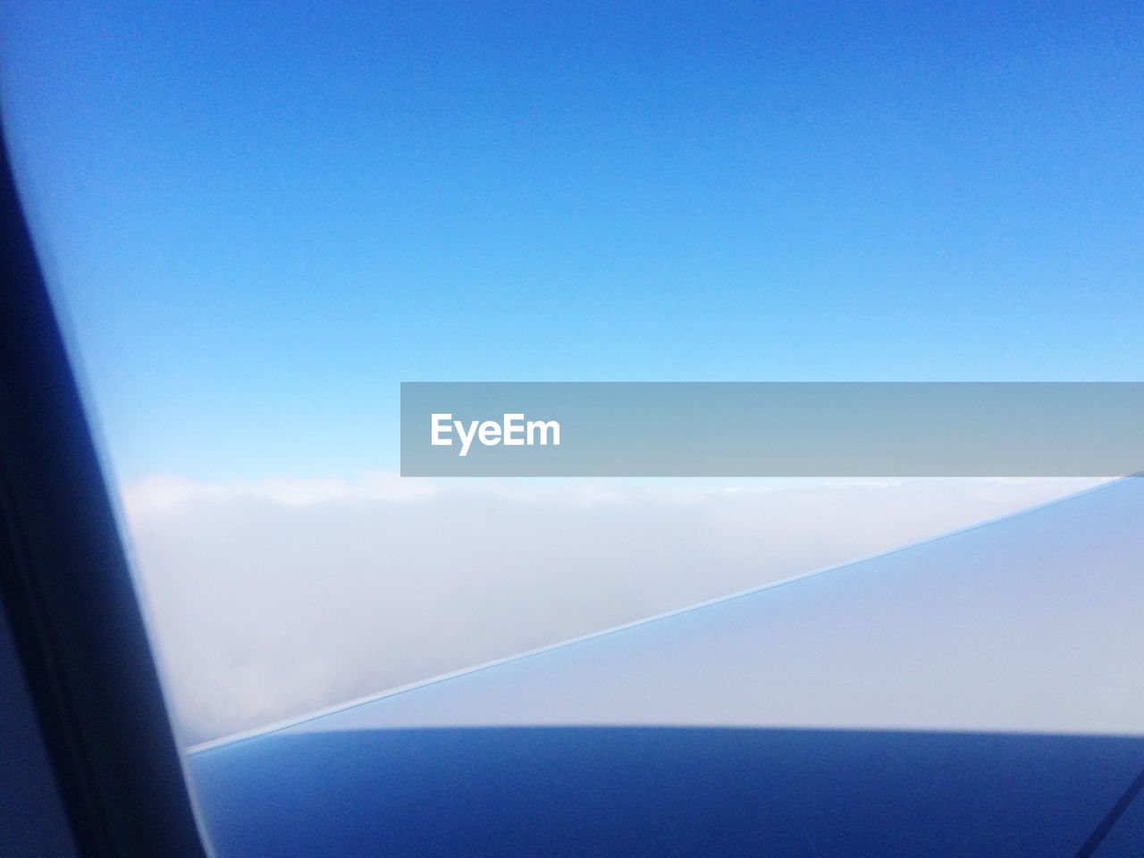Clouds and blue sky seen through airplane window