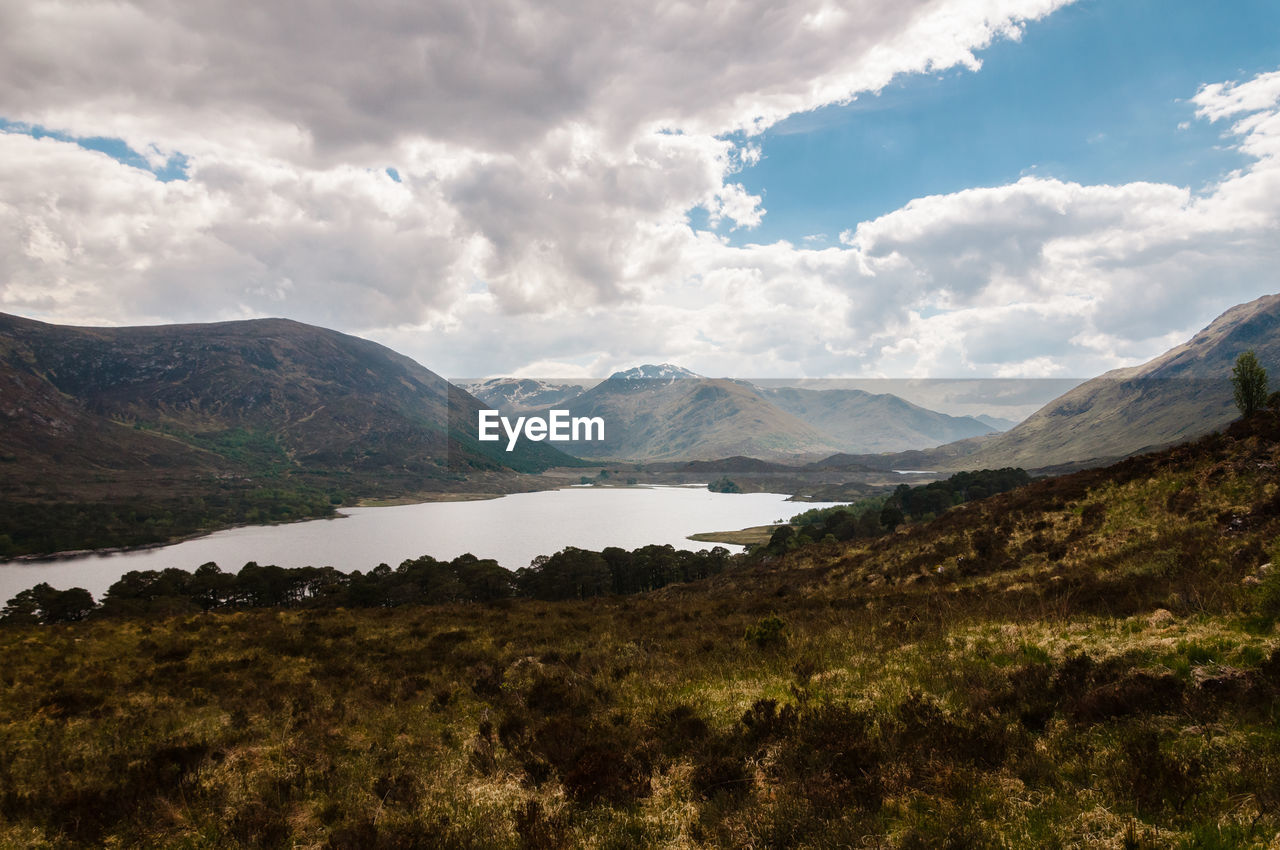 Scenic view of mountains and lake against cloudy sky