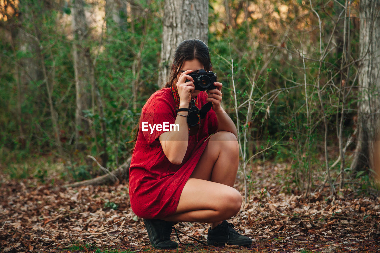 Young woman photographing in forest