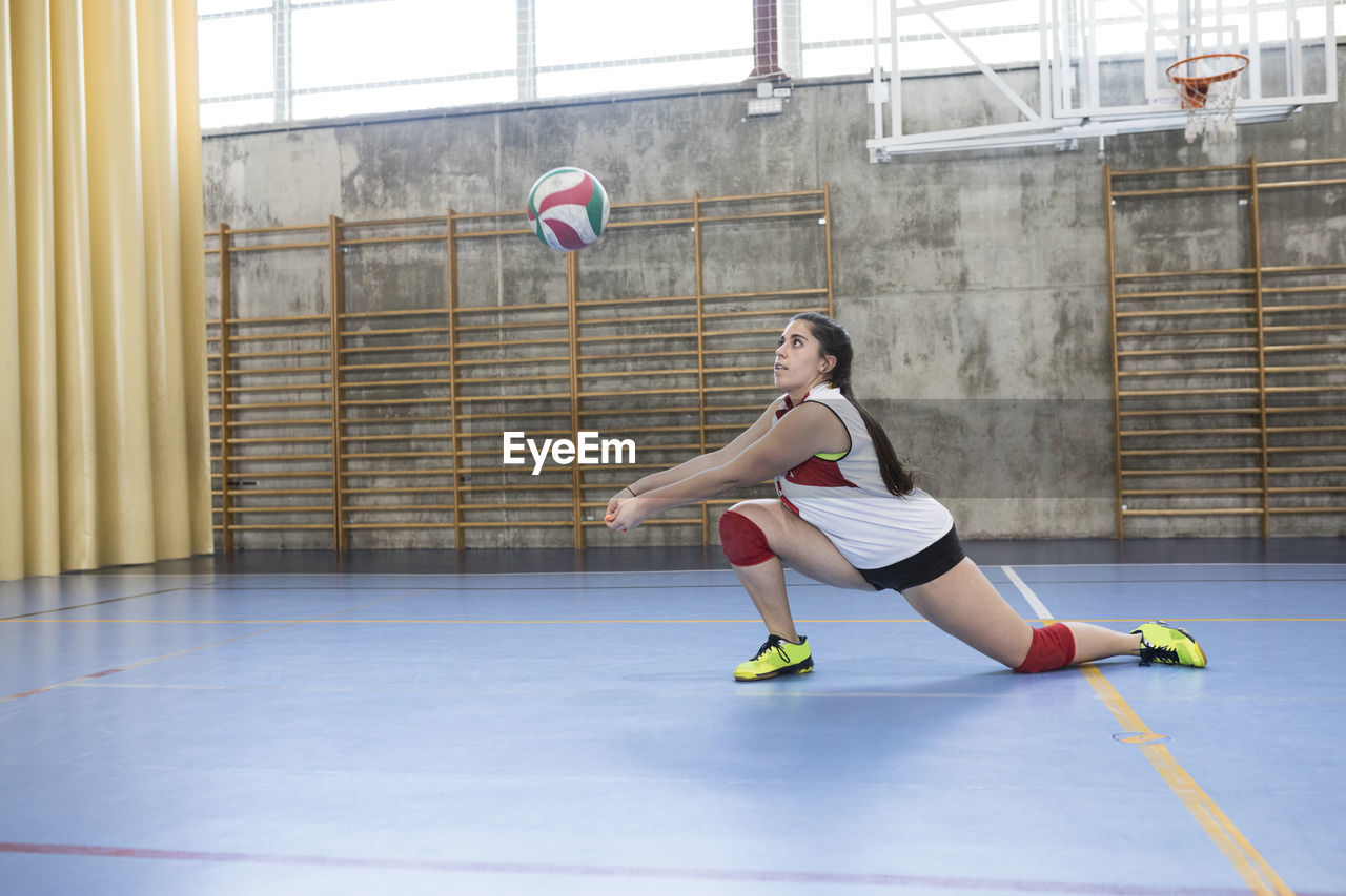 Concentrated female volleyball player hitting ball while tournam