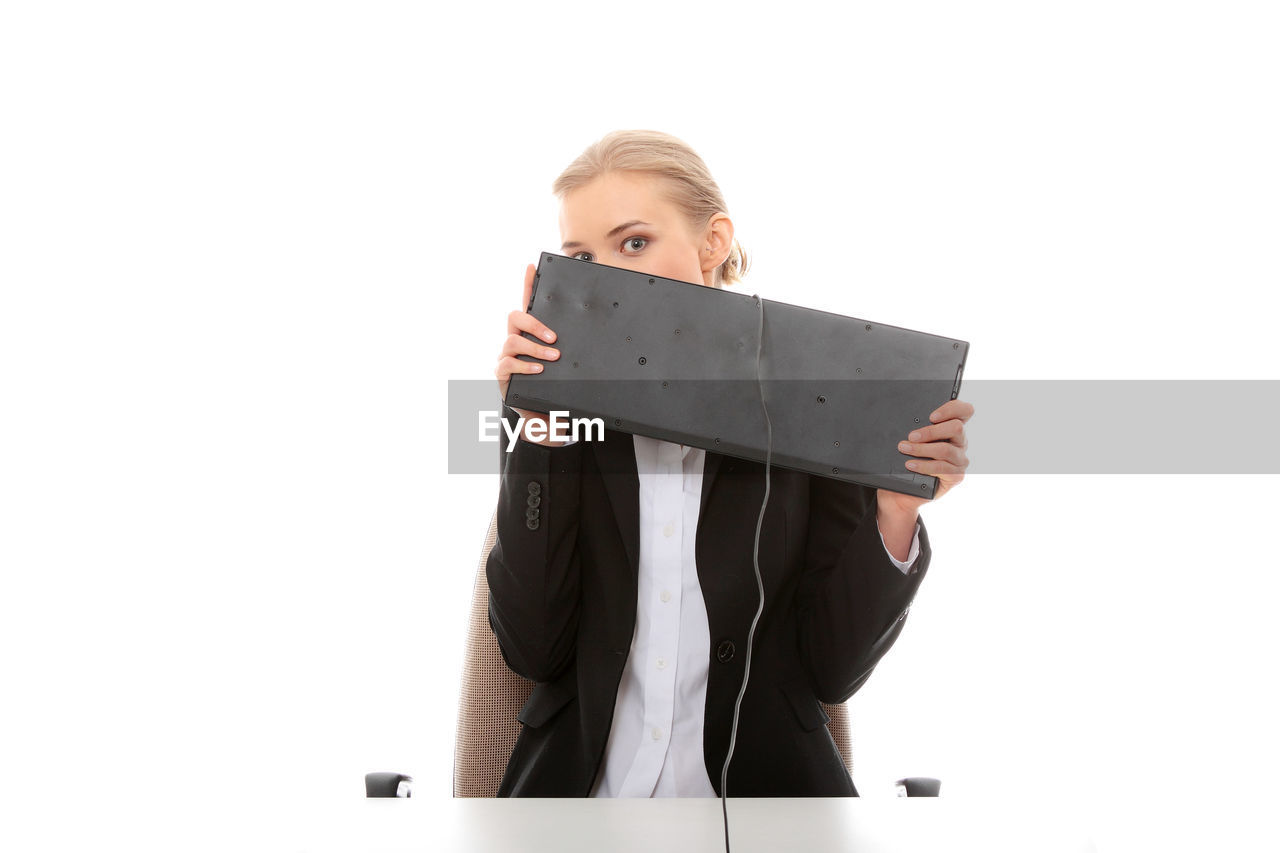 Businesswoman holding keyboard at desk against white background