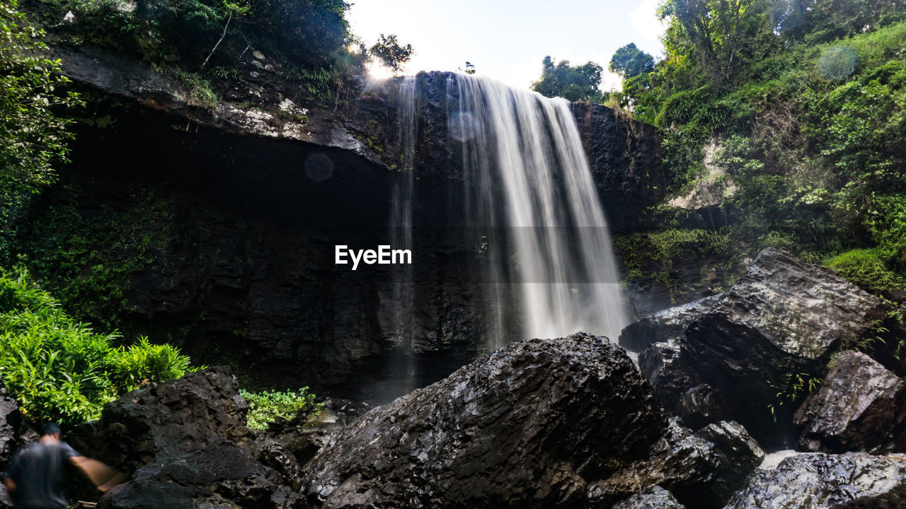 LOW ANGLE VIEW OF WATERFALL IN FOREST AGAINST SKY